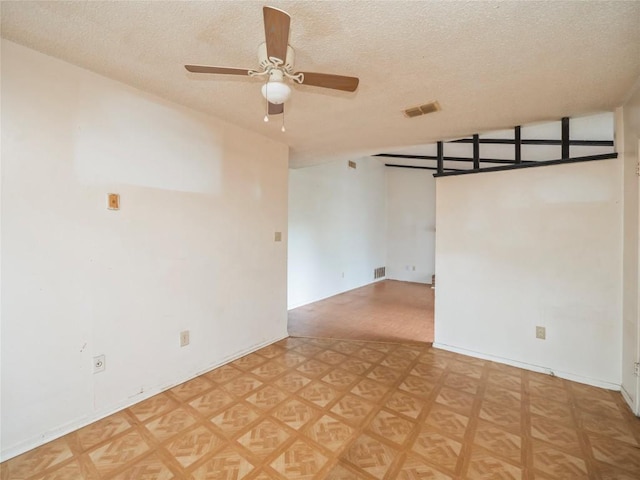 unfurnished room featuring a ceiling fan, visible vents, and a textured ceiling