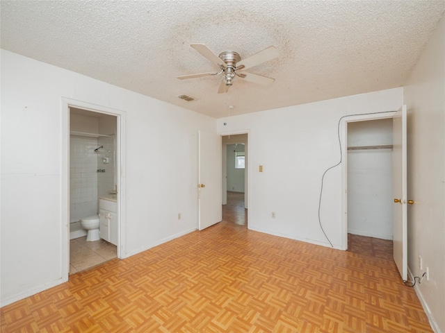 unfurnished bedroom featuring light parquet floors, connected bathroom, and a textured ceiling