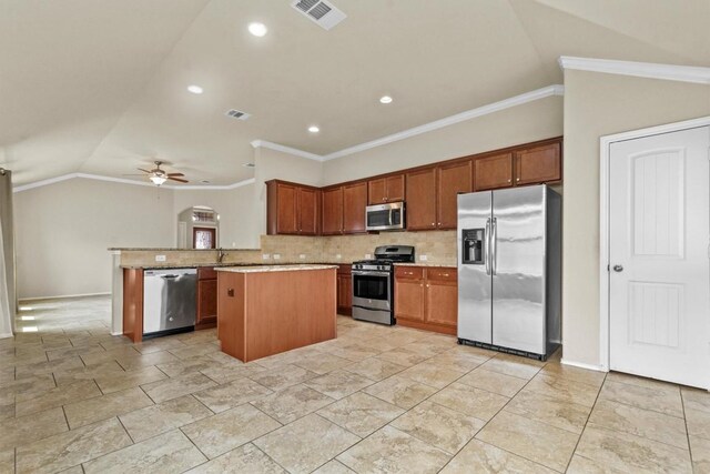 kitchen with a kitchen island, vaulted ceiling, appliances with stainless steel finishes, and crown molding