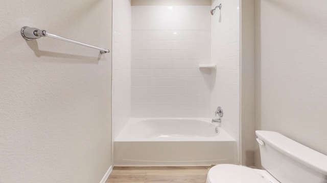 bathroom with hardwood / wood-style flooring, tiled shower / bath, and toilet