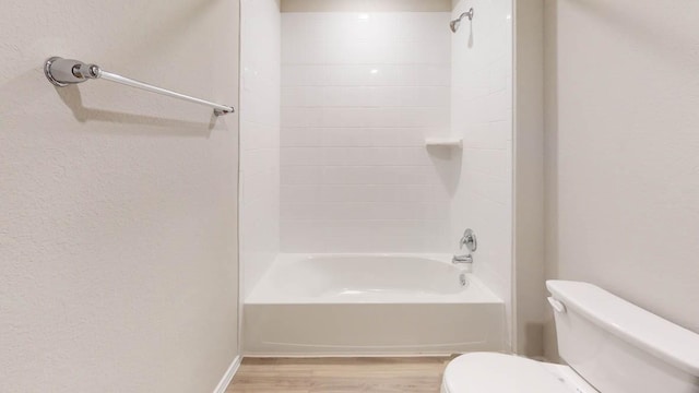 bathroom featuring tiled shower / bath combo, hardwood / wood-style floors, and toilet