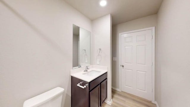 bathroom with vanity, toilet, and hardwood / wood-style floors