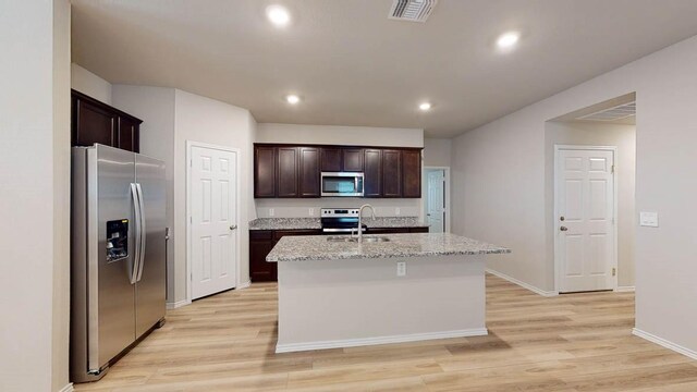 kitchen featuring an island with sink, appliances with stainless steel finishes, sink, and light hardwood / wood-style flooring