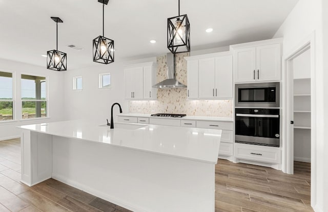 105 Riversong Cv, Georgetown, TX 78633 - kitchen with stainless steel appliances, wall chimney exhaust hood, a sink, light wood-type flooring, and backsplash