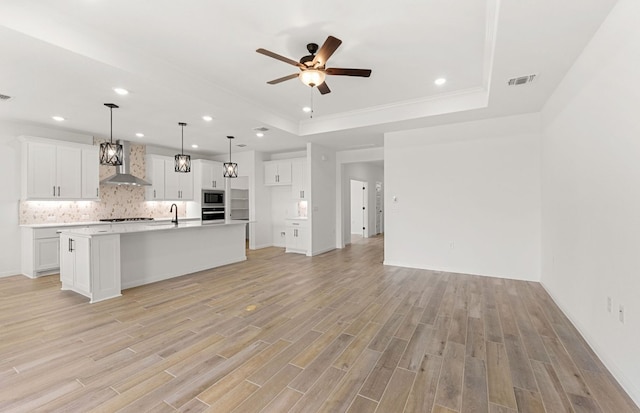 105 Riversong Cv, Georgetown, TX 78633 - kitchen featuring stainless steel appliances, a tray ceiling, wall chimney range hood, ceiling fan, and recessed lighting