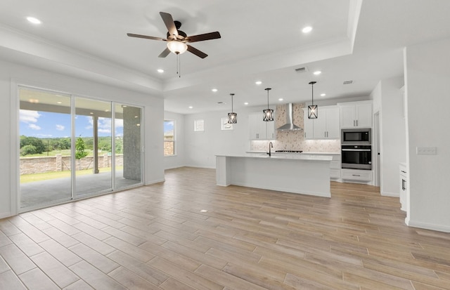 105 Riversong Cv, Georgetown, TX 78633 - unfurnished living room with a tray ceiling, a ceiling fan, recessed lighting, a sink, and baseboards