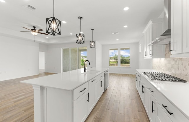 105 Riversong Cv, Georgetown, TX 78633 - kitchen featuring a sink, wall chimney range hood, light wood-style flooring, recessed lighting, and light countertops