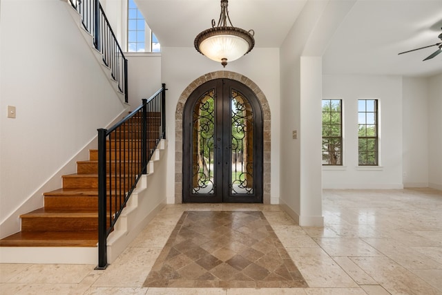 foyer entrance with light tile patterned flooring, french doors, ceiling fan, and a wealth of natural light