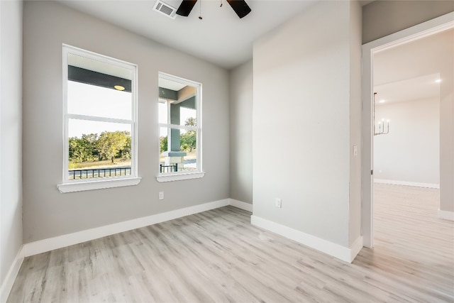 empty room featuring ceiling fan with notable chandelier and light wood-type flooring