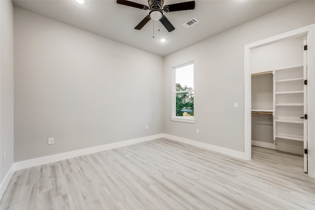 unfurnished bedroom with a walk in closet, ceiling fan, light hardwood / wood-style floors, and a closet