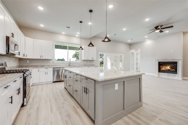 kitchen with light hardwood / wood-style floors, a center island, white cabinets, and stainless steel appliances