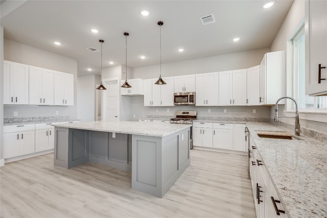 kitchen featuring sink, a center island, appliances with stainless steel finishes, and light wood-type flooring