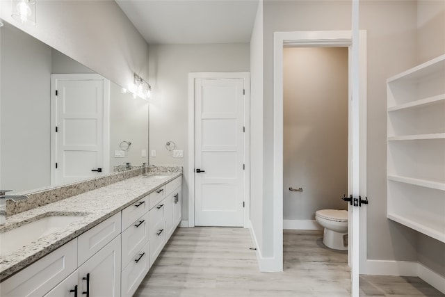 bathroom featuring dual vanity, toilet, and hardwood / wood-style floors