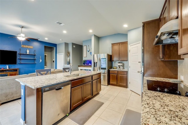 kitchen featuring light stone counters, stainless steel appliances, extractor fan, sink, and a center island with sink