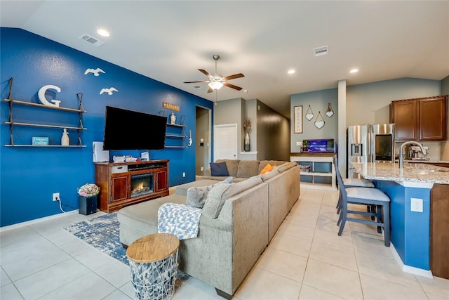 living room with ceiling fan, sink, light tile patterned floors, and vaulted ceiling