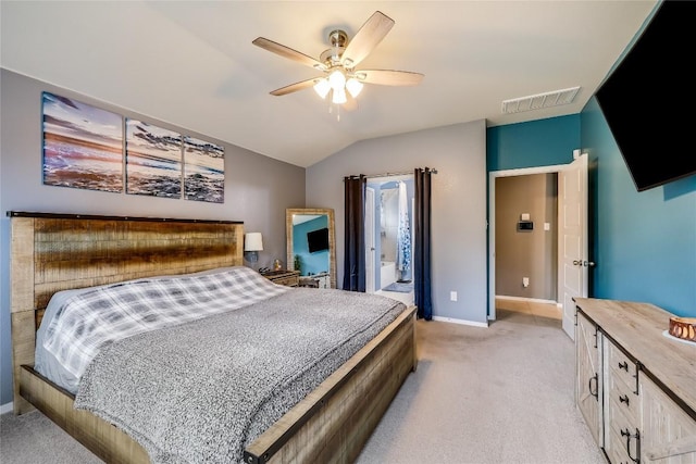 bedroom featuring light carpet, connected bathroom, vaulted ceiling, and ceiling fan