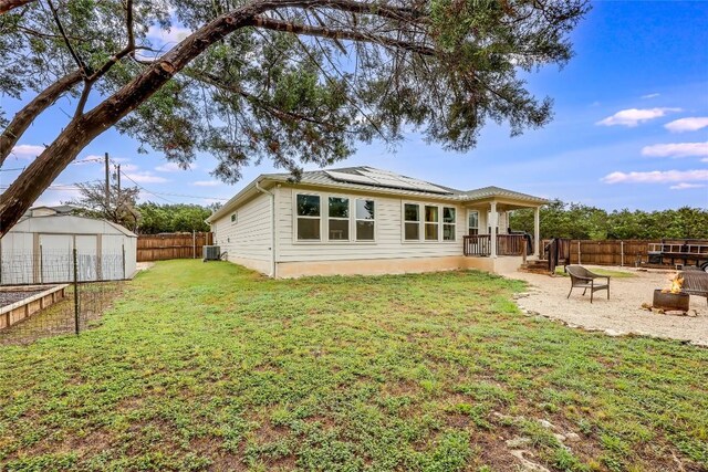 20400 Bear Rd, Lago Vista, TX 78645 - back of property featuring an outdoor fire pit, roof mounted solar panels, and cooling unit