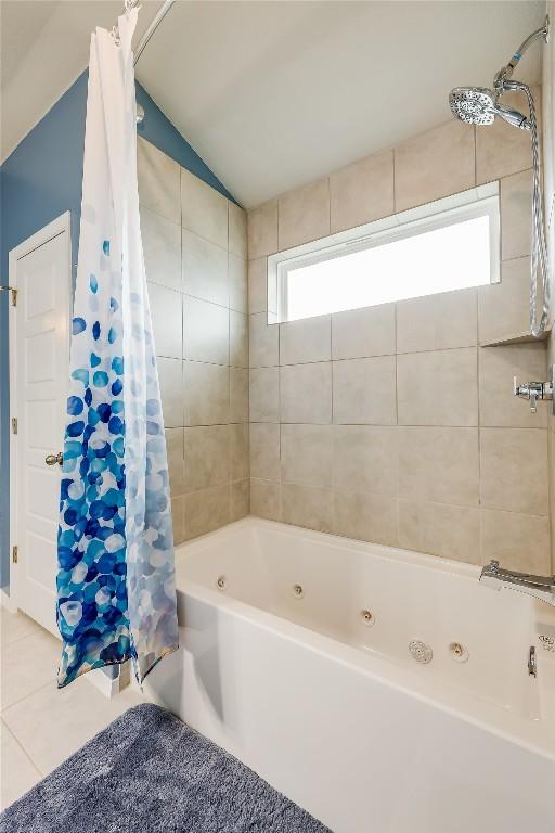 bathroom featuring vaulted ceiling, tile patterned floors, and shower / bathtub combination with curtain