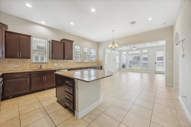 kitchen featuring plenty of natural light, light stone countertops, tasteful backsplash, and light tile patterned floors