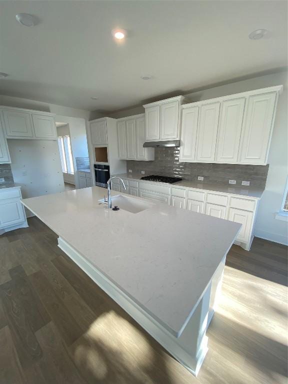 kitchen with white cabinetry, sink, black gas stovetop, an island with sink, and decorative backsplash