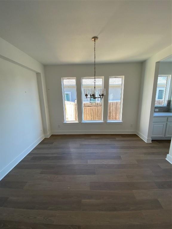 unfurnished dining area featuring a chandelier, dark hardwood / wood-style flooring, and a healthy amount of sunlight