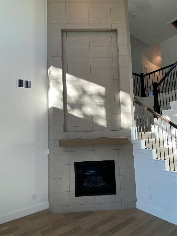 details with wood-type flooring and a tile fireplace