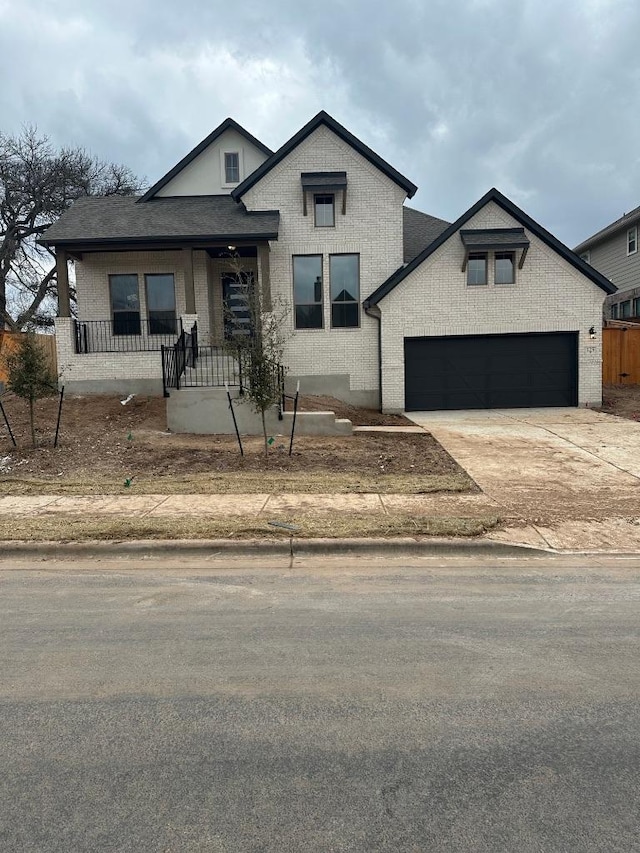 view of front of home featuring covered porch, concrete driveway, brick siding, and an attached garage