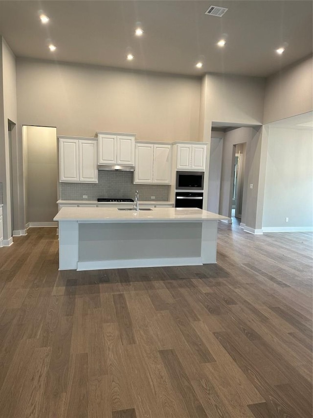 kitchen with a towering ceiling, stainless steel microwave, a sink, and oven