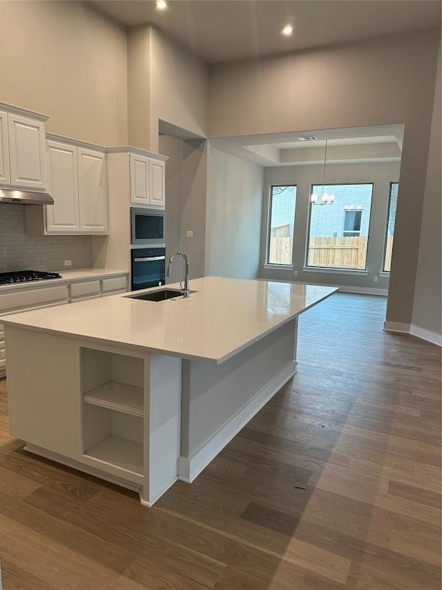 kitchen with wall oven, under cabinet range hood, stainless steel microwave, white cabinetry, and black stovetop