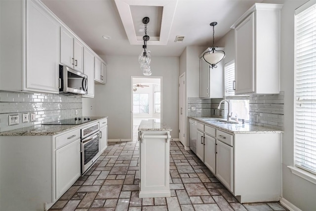 kitchen with sink, decorative light fixtures, appliances with stainless steel finishes, a kitchen island, and white cabinets