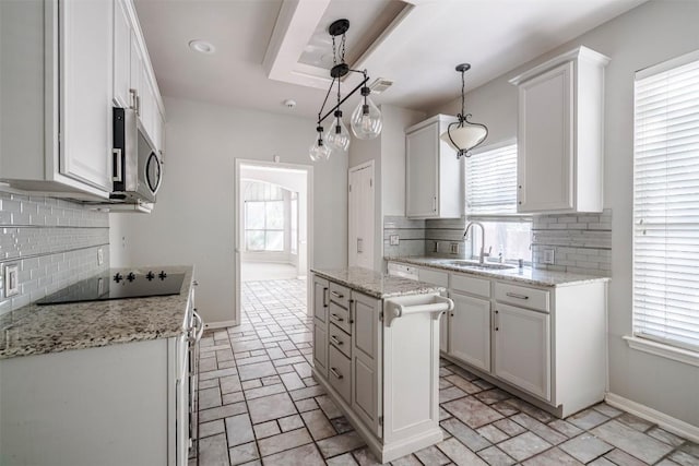 kitchen with white cabinetry, black electric cooktop, a center island, and hanging light fixtures