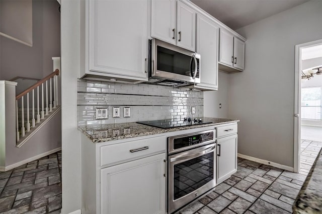 kitchen featuring decorative backsplash, light stone countertops, white cabinets, and appliances with stainless steel finishes