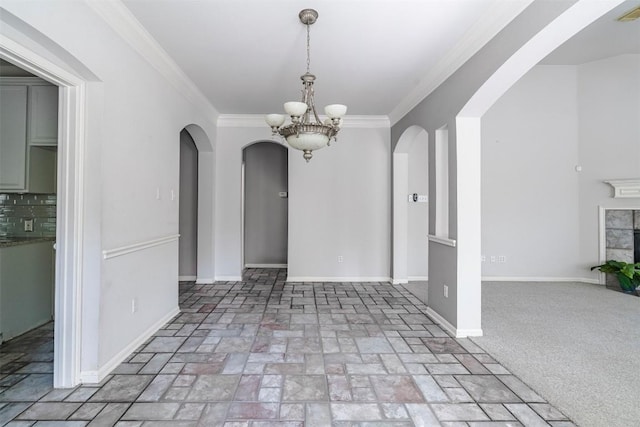 unfurnished dining area featuring ornamental molding, a fireplace, and a chandelier