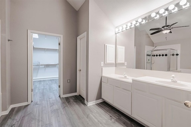 bathroom featuring vaulted ceiling, hardwood / wood-style flooring, vanity, ceiling fan, and walk in shower