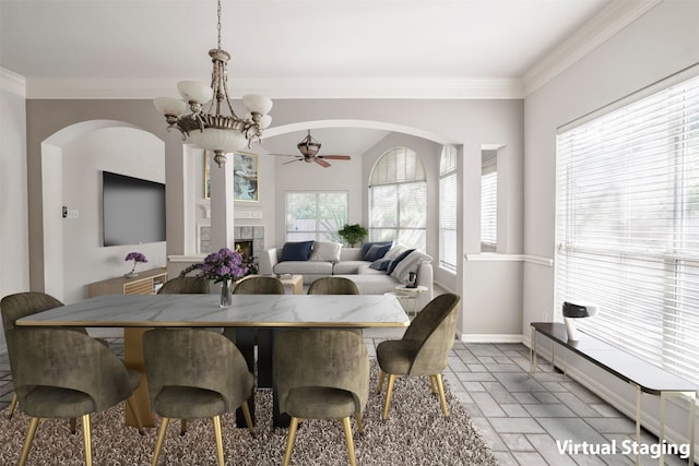 dining area with crown molding, a fireplace, and ceiling fan with notable chandelier