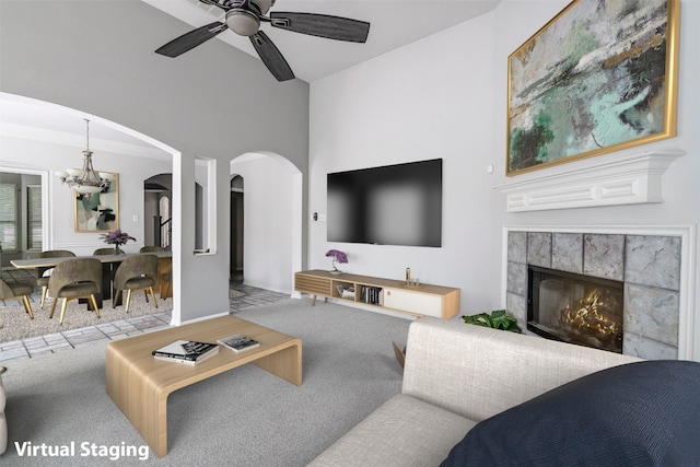 living room featuring light carpet, ceiling fan with notable chandelier, and a tile fireplace