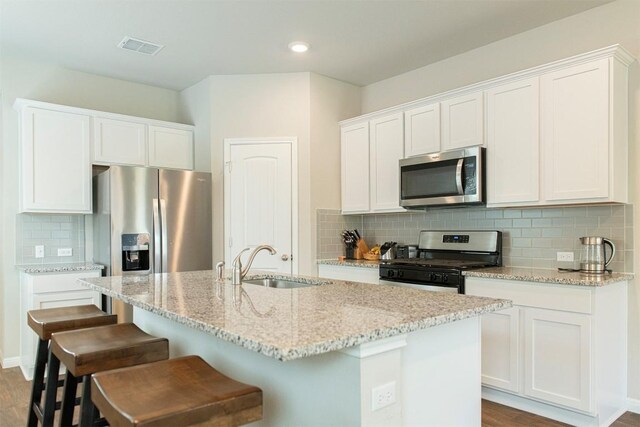 kitchen featuring tasteful backsplash, stainless steel appliances, white cabinets, sink, and hardwood / wood-style flooring