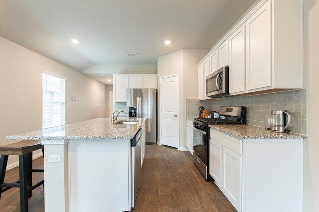 kitchen with tasteful backsplash, stainless steel appliances, white cabinets, an island with sink, and dark hardwood / wood-style floors