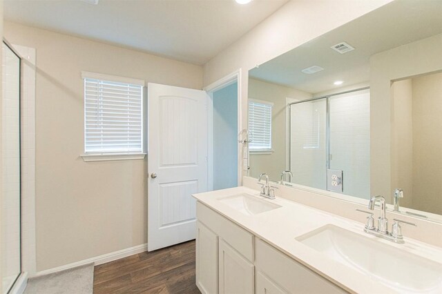 bathroom with double vanity, walk in shower, and wood-type flooring