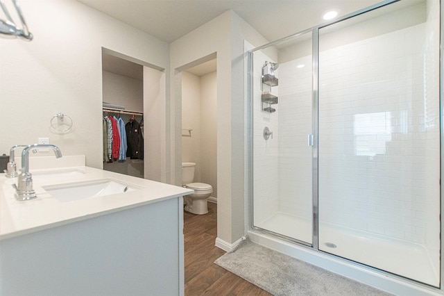 bathroom with a shower with door, vanity, wood-type flooring, and toilet