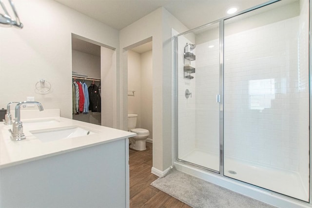 bathroom with hardwood / wood-style flooring, vanity, an enclosed shower, and toilet