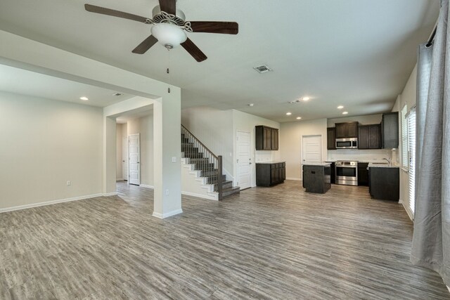 unfurnished living room featuring hardwood / wood-style floors, sink, and ceiling fan