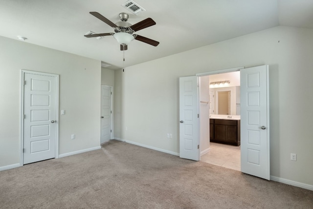 unfurnished bedroom featuring ensuite bathroom, light carpet, ceiling fan, and vaulted ceiling