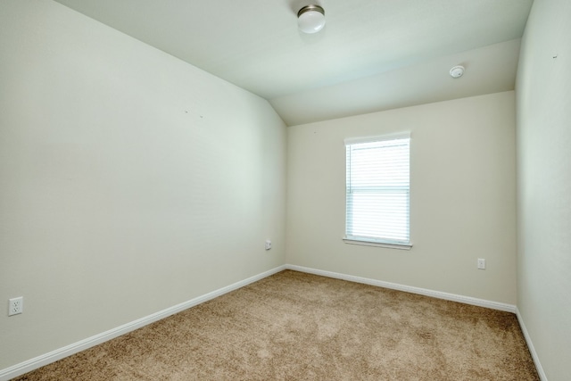 unfurnished room featuring light carpet and vaulted ceiling