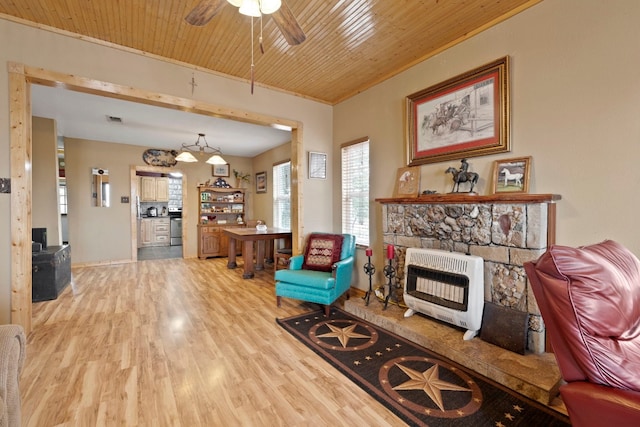 living room with heating unit, a fireplace, ceiling fan, and light hardwood / wood-style floors