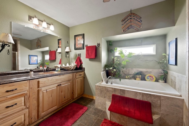 bathroom featuring tiled tub, vanity, and tile patterned floors