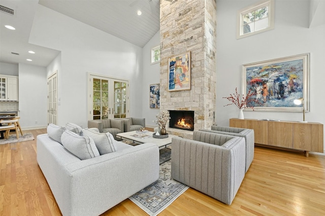 living room featuring a stone fireplace, light wood-type flooring, and high vaulted ceiling