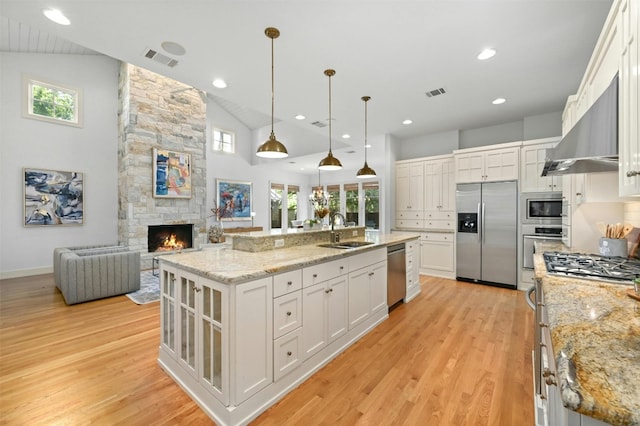 kitchen featuring sink, an island with sink, white cabinetry, vaulted ceiling, and stainless steel appliances