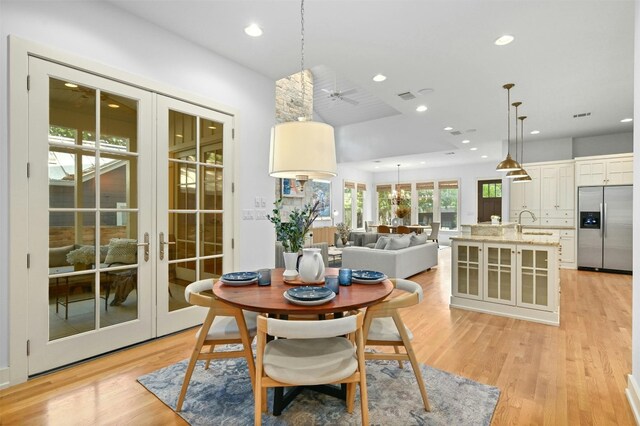 dining space with sink, light hardwood / wood-style flooring, french doors, and ceiling fan