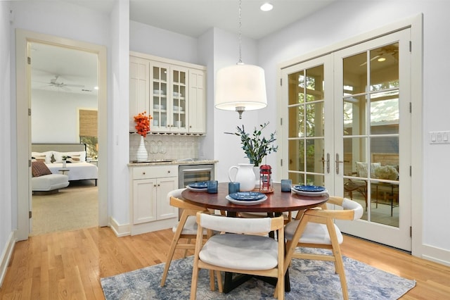 dining space with light wood-type flooring, ceiling fan, beverage cooler, and french doors